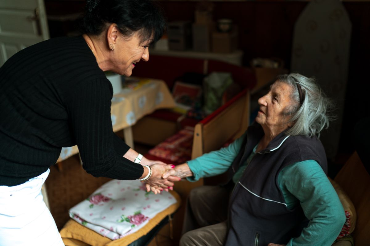 Una cuidadora y una mujer mayor se saludan con cercanía en el hogar