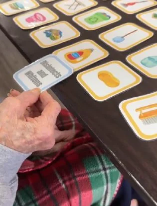 Una persona mayor participa en una actividad cognitiva con tarjetas.