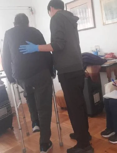 Una cuidadora acompaña a una persona mayor mientras camina en casa.